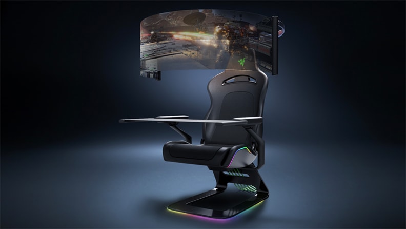 A retractable display screen encircles a Razer gaming chair for bleeding-edge immersion. There are colored lights along the edges of the chair.