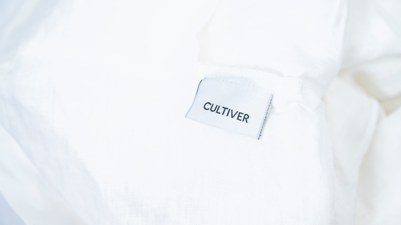 A closeup of the Cultiver logo on a set of linen sheets.