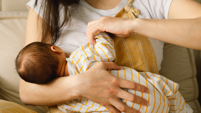 Person breastfeeding newborn baby.