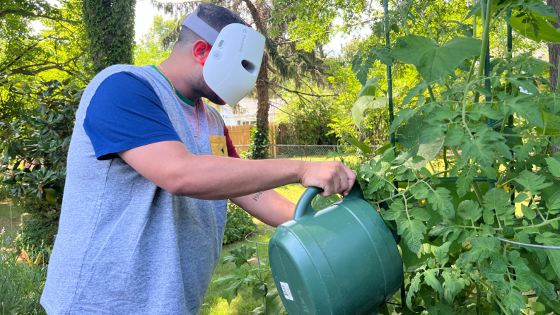 Man watering plants wearing a TheraFace mask.