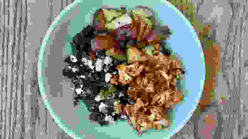 烤花椰菜、土豆和羽衣甘蓝沙拉，放在薄荷绿色的碗里。