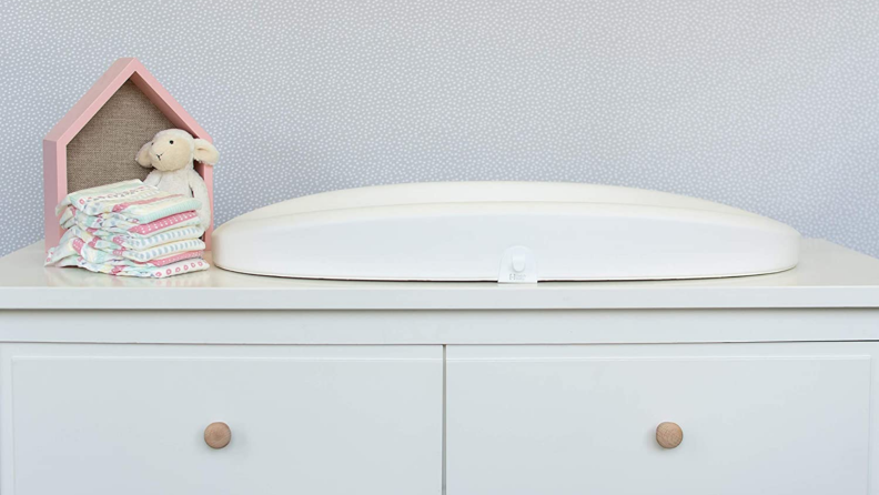 White changing table on top of dresser.