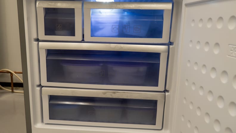 A close-up photo of Beko's freezer compartment.  It has two full-width drawers under it, and its top row holds a small bin for the ice maker and another large storage bin.