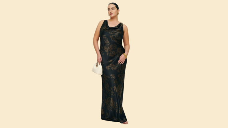 A model wearing a black floor-length gown with a subtle floral print.