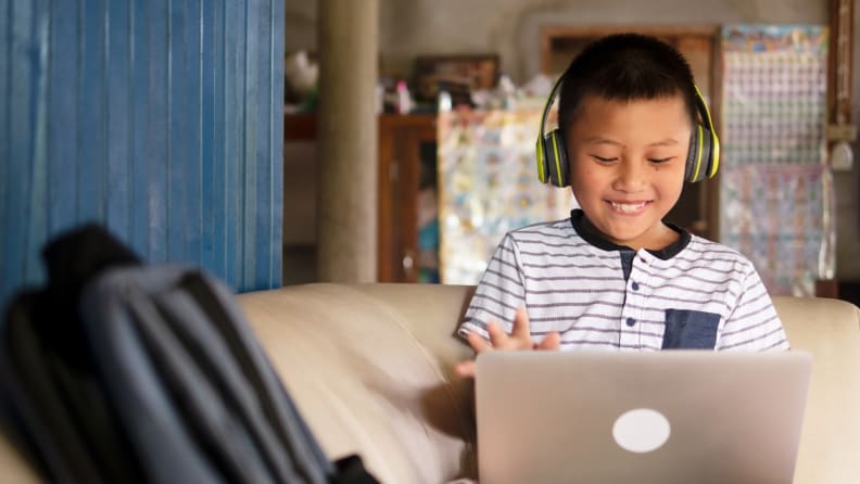 Child smiling while using laptop.