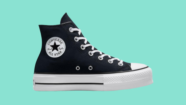 Black Chuck Taylor high top shoe against teal background