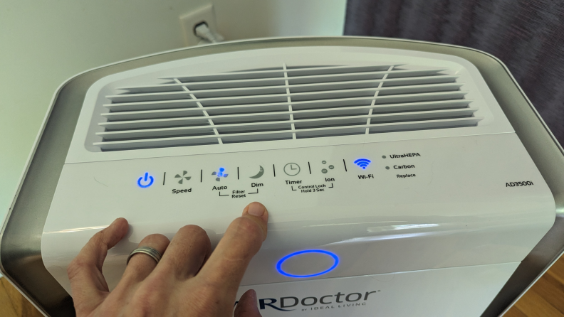 A hand touches the top of the Air Doctor Pro 3500i.