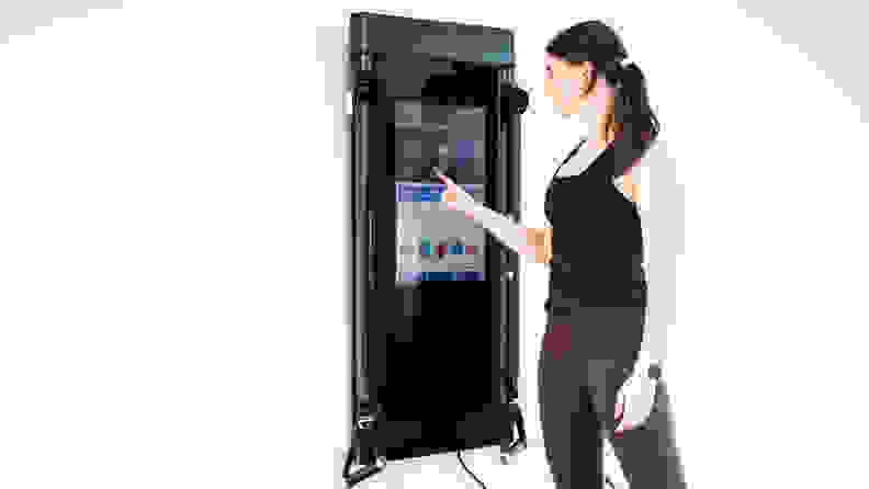 A woman selecting a workout on Tonal's touchscreen.