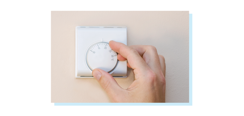 Person adjusting the in-home thermometer mounted on wall.