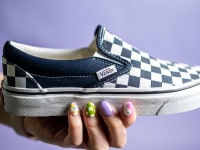 Close-up on a hand holding the Vans Checkboard slip-on.