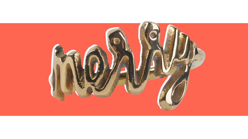 An image of a golden napkin ring shaped with the word "merry" in cursive.