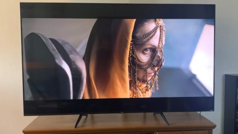 An image of Rebecca Ferguson in Dune displayed on a TCL 5-Series TV on a wooden credenza.