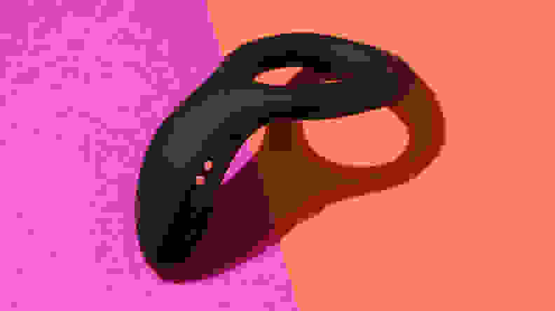 The Lovense Diamo vibrating cock ring on top of a pink and orange contrast surface.