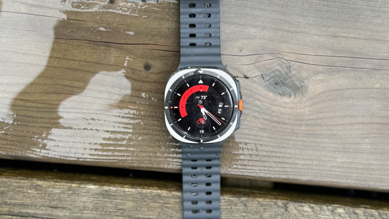 A Samsung Galaxy Watch Ultra laying on a wet patio deck outdoors.