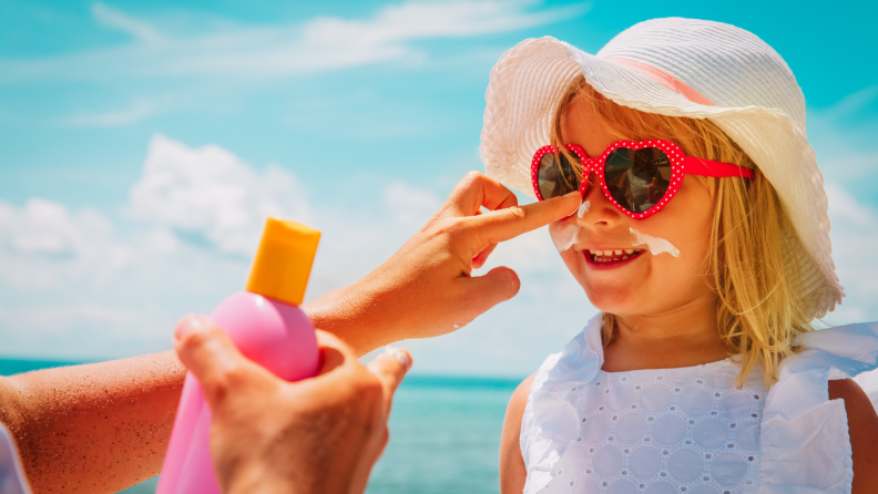 parent putting sunscreen on little girl