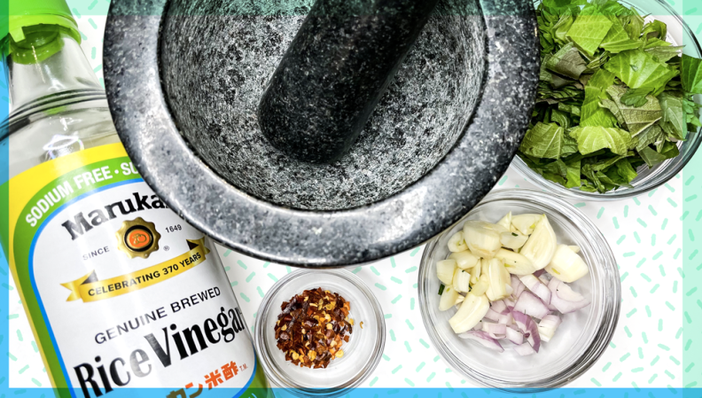 Ingredients for chimichurri arranged around a mortar and pestle.
