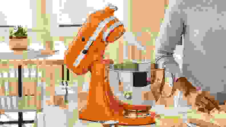 An orange stand mixer with its head tilted