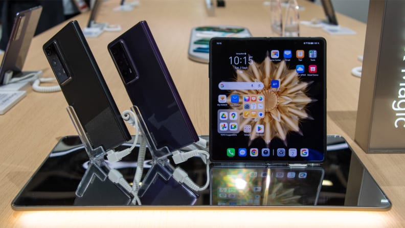 Two smartphones and a tablet shown side by side on showcase stands.