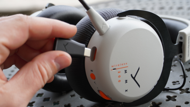 A person plugging a USB cord into the Beyerdynamic MMX 200 headphones.