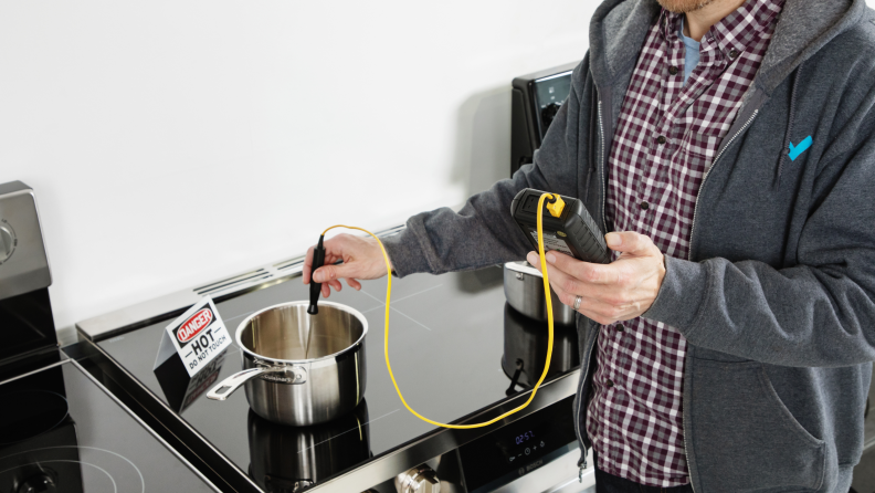 A Reviewed Kitchen editor testing the burners on the range's with a thermostat.