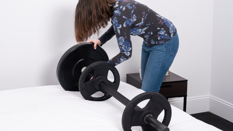 Our tester places weights on a barbell that's sitting on a mattress.