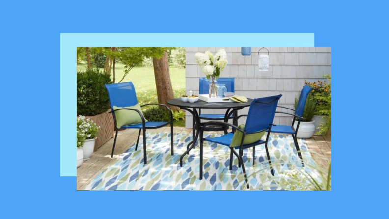 A blue and green print rug on a patio against a blue background.