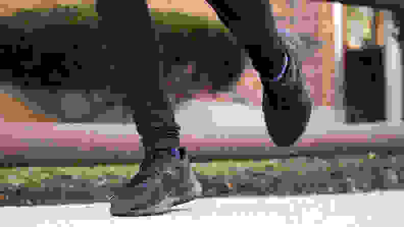 Feet running dow the sidewalk in black Lululemon sneakers