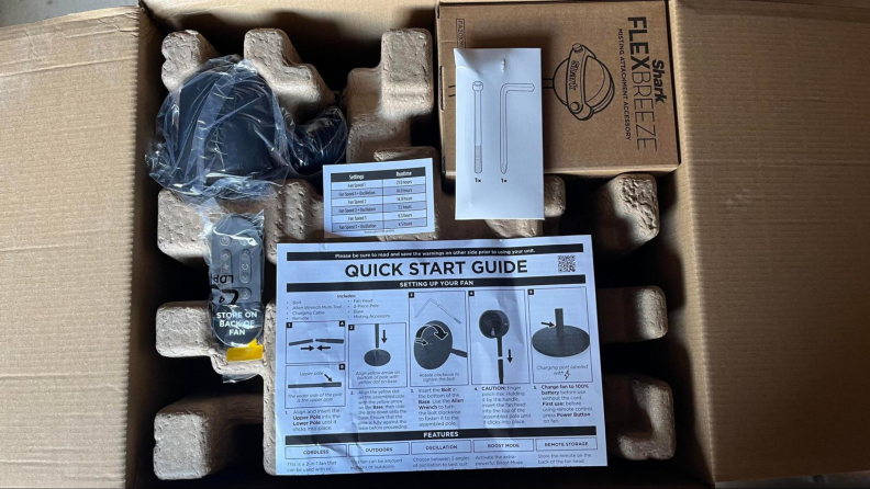 A look inside the Shark FlexBreeze box featuring an instruction manual, remote control, plug, and other accessories.