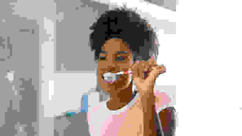 A photo of a girl brushing her teeth.