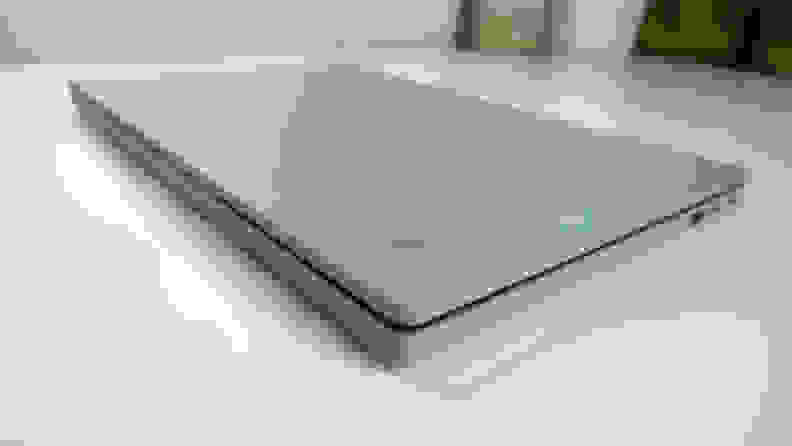 A light gray laptop, closed, on top of a white desk