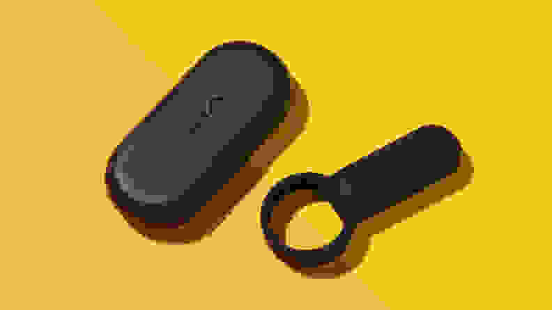 The Tenga SVR vibrating cock ring next to its travel case on top of a two-tone yellow and orange surface.