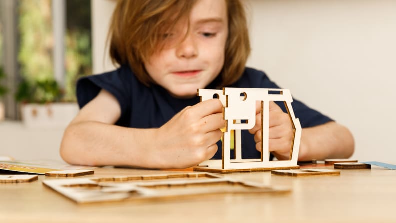 A boy puts together a toy tuk-tuk car.