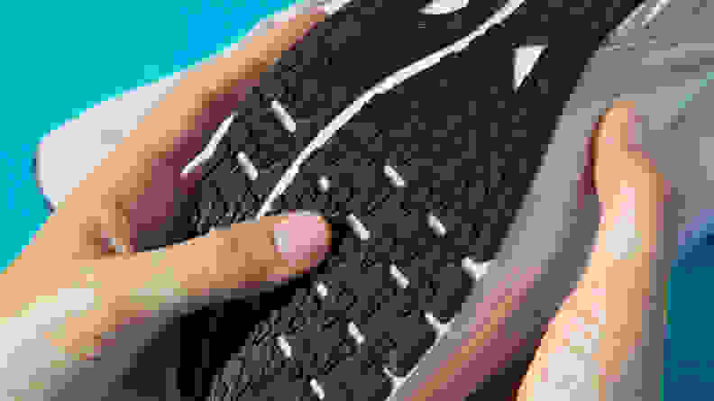 A person touches the black outsole of a running shoe.