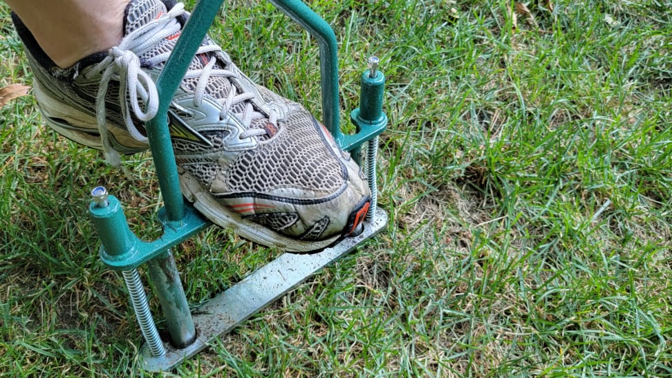 A sneaker driving in an aerator into compacted grassy soil