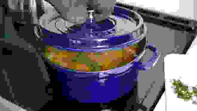 Blue cocotte with stew inside on stove