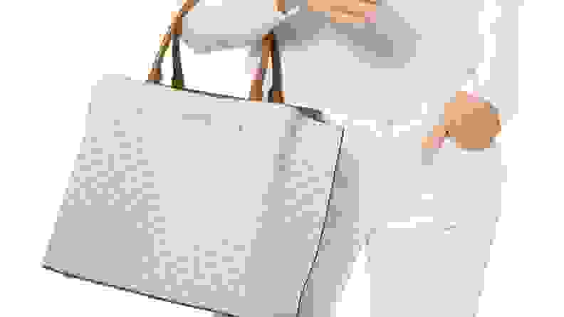 A woman in white holding a white Michael Kors bag.