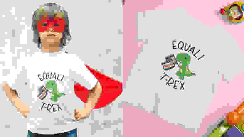 Child wearing a red cape posing like a superhero wearing a white tshirt with a dinosaur on it holding a rainbow flag with the pun "Equali T-Rex". Next to that, is the same white tshirt lying on a pink background.