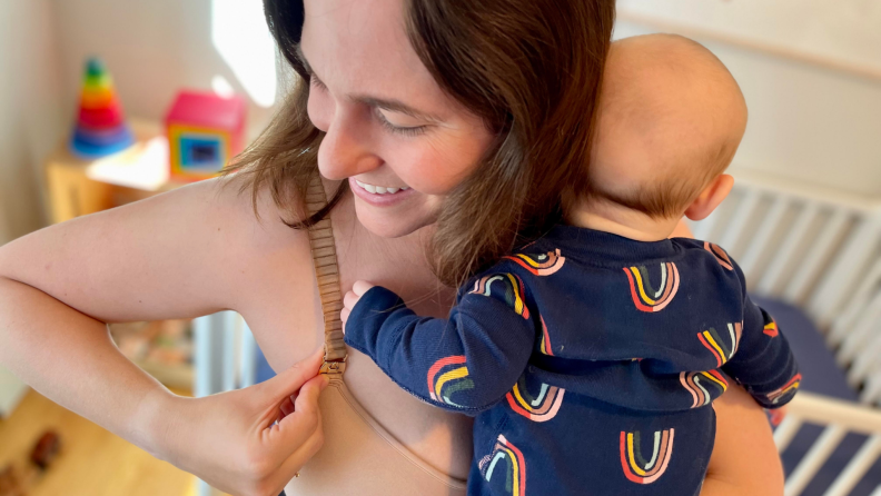 A parent clasps their Thirdlove 24/7 Classic Nursing Bra strap while holding an infant.