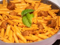 A pot of manicotti pasta cooked in tomato sauce with meatballs in an Always pan.