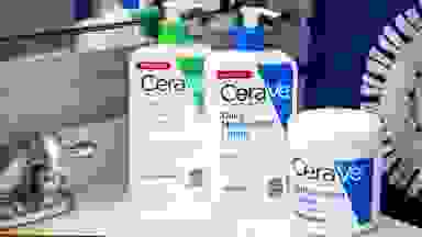 A Cerave cleanser and two moisturizers sit on a bathroom sink.