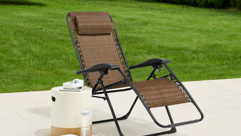 a brown outdoor chair sits on a patio in a backyard