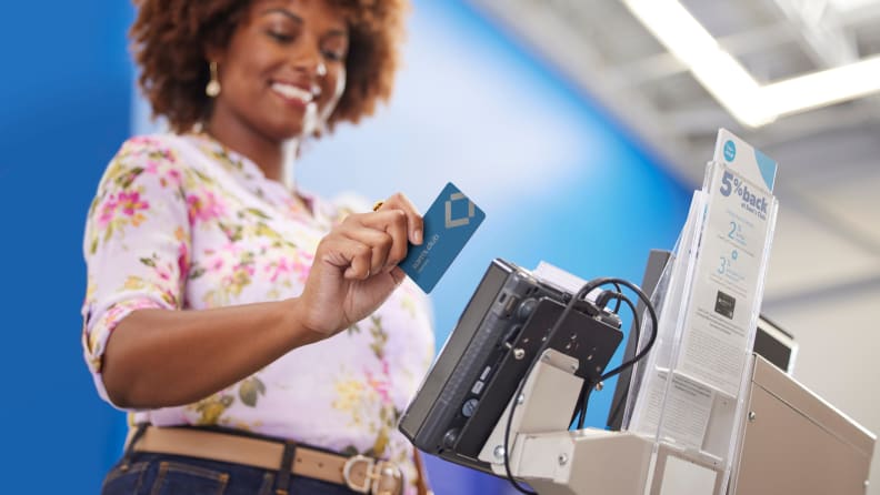 A woman uses her Sam's Club credit card at checkout, highlighting the perks and rewards of membership shopping.