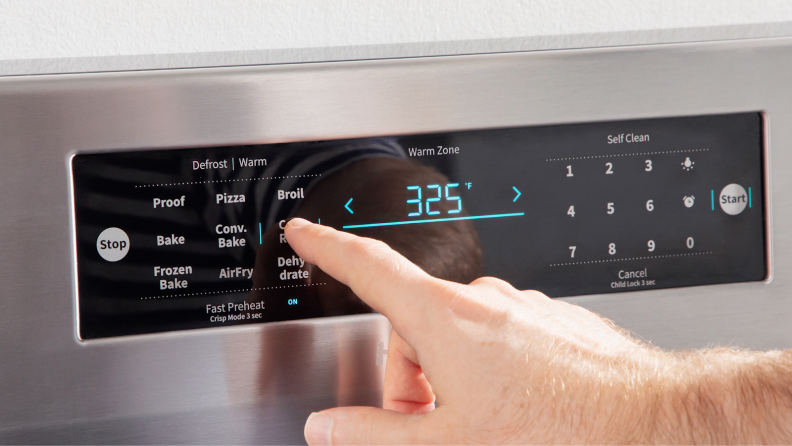 Person using finger to press setting on Hisense electric range display.