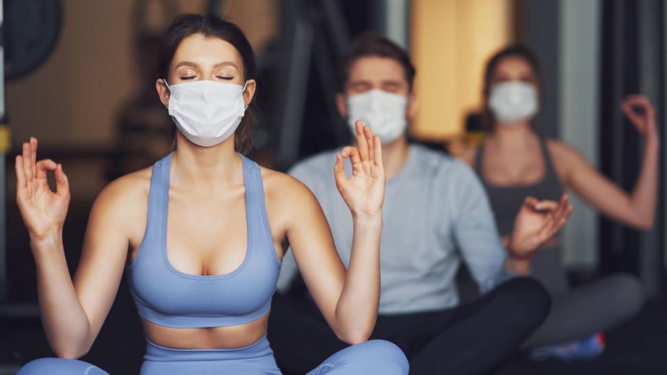 three people taking a yoga class wearing masks