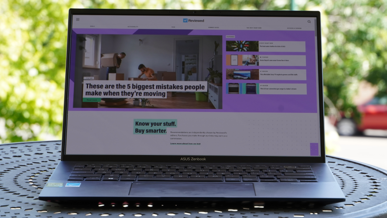 An open laptop sits on a patio table outside.