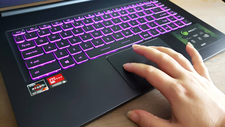 A hand touching a laptop's trackpad