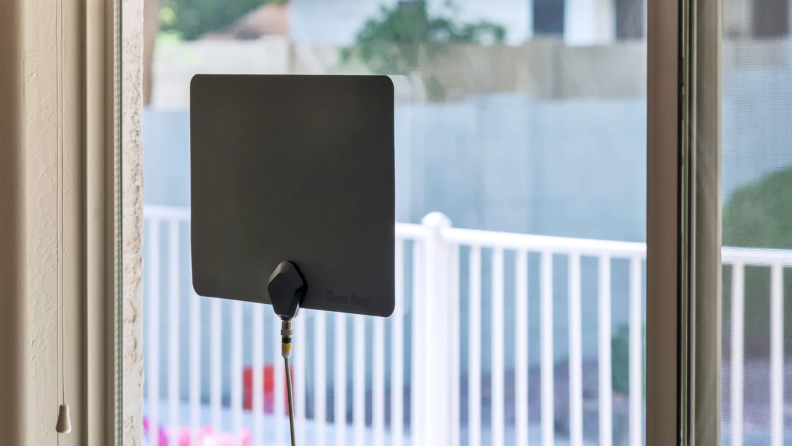 A black Channel Master Flatenna indoor TV antenna mounted on a window.
