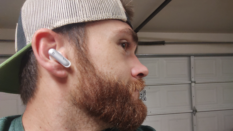 A man with a beard wearing a white earbud