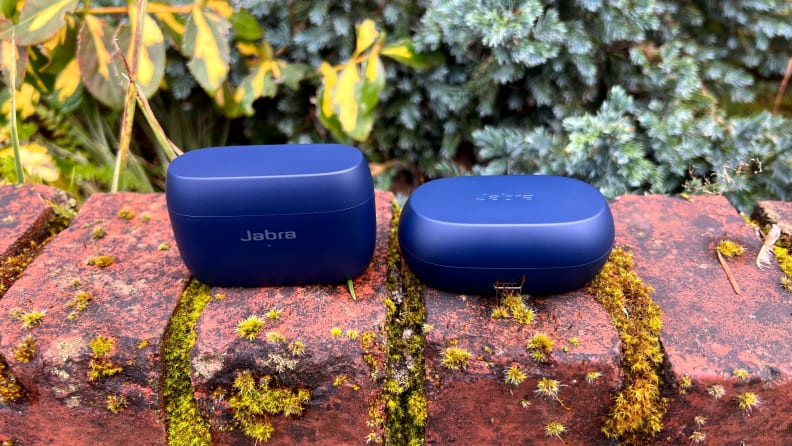 The Elite 4 Active and Elite 7 Active headphones sit in closed navy cases on a mossy brick ledge.