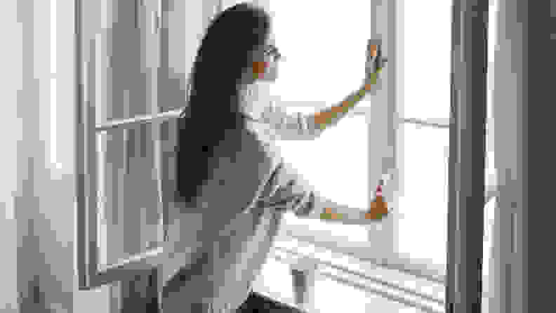 A woman opening a sunlit window